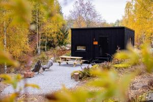 a black shed with a picnic table and a bench at Nest Away in Strängnäs