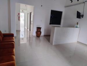 a white living room with a television and a couch at ABA Hotel in Belém +3 photos
