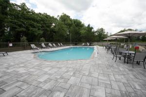a swimming pool with chairs and a table and an umbrella at DoubleTree by Hilton Tinton Falls-Eatontown in Tinton Falls