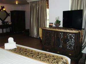 a bedroom with a bed with a television on top of a dresser at Eagle Bay Hotel in Kuah