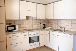 a kitchen with white cabinets and a sink and a microwave at Chalet Suveran 2 in Arosa