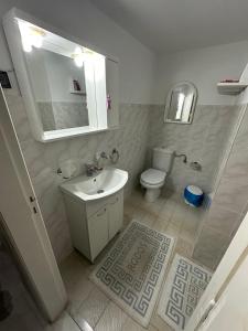 a white bathroom with a sink and a toilet at Giulia's Beach House in Rhodes Town