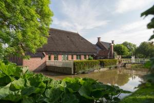 a house next to a river with a bridge at Landgoedlogies Pábema in Zuidhorn