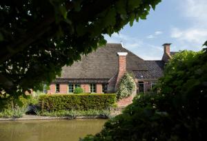 a large brick house with a black roof at Landgoedlogies Pábema in Zuidhorn +14 photos