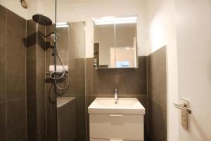 a bathroom with a sink and a shower with a mirror at Design Terrassenwohnung in Schwieberdingen
