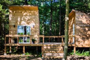 a wooden house with two potted plants on a deck at The Green Acres Cabin in Hamilton