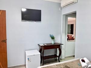 a room with a desk and a television on a wall at Pousada Tia Alice in Penha