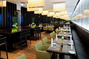 a dining room with tables and chairs and chandeliers at Atlantic Congress Hotel Essen in Essen