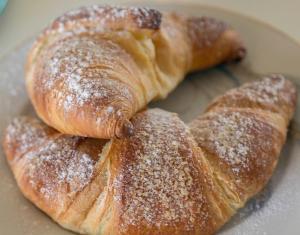 three croissants on a plate with powdered sugar at La Dolce Mela in Buonabitacolo +55 photos