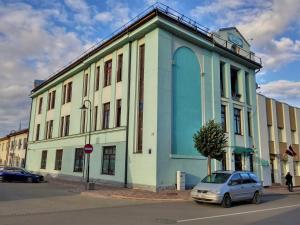 un edificio azul y blanco con un coche aparcado delante en Hotel Ludza, en Ludza