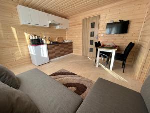 a living room with a table and a kitchen with a refrigerator at Domek wypoczynkowy Górskie Zacisze in Sidzina