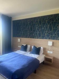 a bedroom with a bed with blue sheets and a wall at Apartament 505 in Mielno