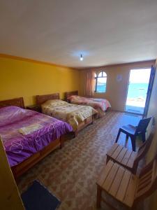 a hotel room with three beds and a window at Hostal Mirador del Sol in Comunidad Challapampa +16 photos