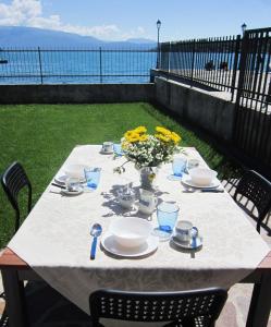 einen Tisch mit einem weißen Tischtuch und gelben Blumen in der Unterkunft Appartamento alle Rive in Salò