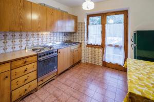 een keuken met houten kasten en een fornuis met oven bij Villa Chiappuzza - Stayincortina in San Vito di Cadore