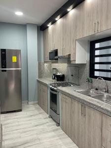 Una cocina con electrodomésticos de acero inoxidable y gabinetes de madera. en Casa hermosa con piscina, en Salinas