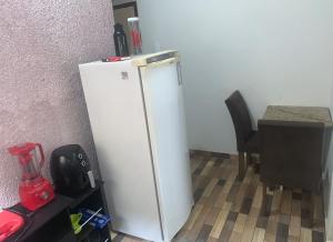 a white refrigerator in a room with a table at Apto Amar - No Espaço Florescer in Campos dos Goytacazes