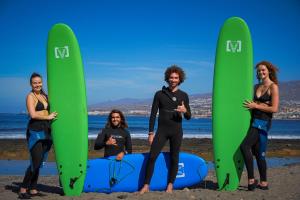 un grupo de personas de pie en la playa con tablas de surf en Single Fin Surf Hostel, en Arona