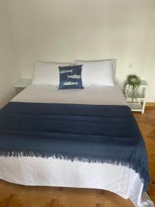 a large bed with a blue and white blanket at Despierta frente al mar en Moaña in Pontevedra