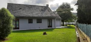 a white house with a green yard with a fence at Maison familiale à Gerde in Gerde