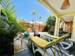 a patio with chairs and a fence and palm trees at BLUE WAVE - 2 bedrooms - Orient Beach! in Orient Bay