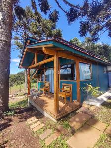 a tiny house with a porch and two chairs at Na'raucária in Cambará