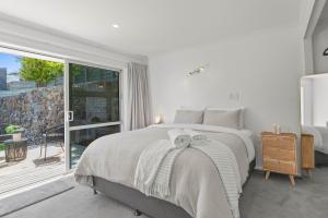 a white bedroom with a bed and a large window at Tuis and Pools - Lake Taupo Holiday Home in Taupo +17 photos