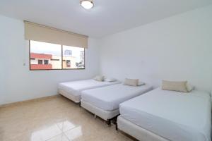 two beds in a room with a window at Hotel Axis Inn By GEH Suites in Santa Marta +58 photos