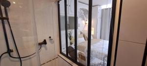 ein Bad mit einer Glasdusche und einem Bett in der Unterkunft Appartement terrasse esprit loft vue sur mer in Erquy