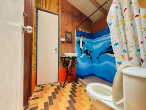a bathroom with a dolphin shower curtain and a toilet at Los Gulungos Hostel in Jardin