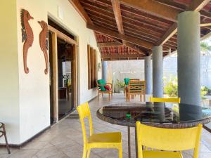 un patio con sedie gialle e tavolo in vetro di Casa de Praia Olivença a Ilhéus