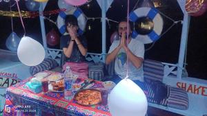 a man and a woman sitting in front of a table with food at Aswan Felucca sailing boat and Hotel in Aswan