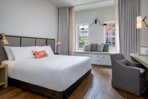 a bedroom with a large white bed and a chair at The Alida, Savannah, a Tribute Portfolio Hotel in Savannah