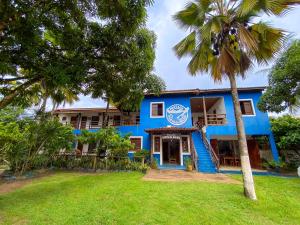 a blue building with a palm tree in front of it at Pousada Ponta da Baleia in Barra Grande