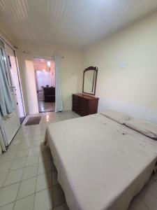 a bedroom with a large white bed and a mirror at Hospedagem Pedro e Maria in Lages +3 photos