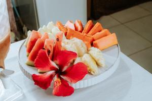 a plate of fruit and vegetables on a table with a flower at Pousada Ponta da Baleia in Barra Grande