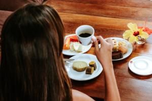 a woman sitting at a table with a cup of coffee at Pousada Ponta da Baleia in Barra Grande