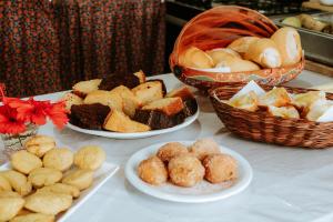 a table with three plates of food and baskets of bread at Pousada Ponta da Baleia in Barra Grande