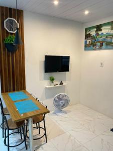 a dining room with a table and a tv on a wall at Casa de praia Rocha Alves em Porto de Galinhas in Porto De Galinhas