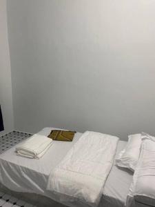 Una cama blanca con sábanas y almohadas blancas. en Rina Homestay 2, en Kuala Terengganu