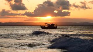 a boat in the ocean with the sunset in the background at Pousada Ponta da Baleia in Barra Grande