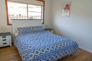 Un dormitorio con una cama con edredón azul y una ventana. en Sea La Vie managed by Batemans Bay Accom, en Sunshine Bay