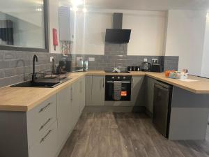 a kitchen with white cabinets and a black dishwasher at Belmont House in The Mumbles