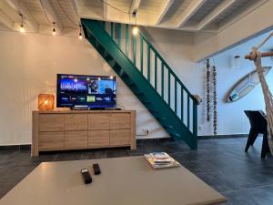 a living room with a tv and a staircase at Appartement spacieux au village du flamboyant in Baie Nettle