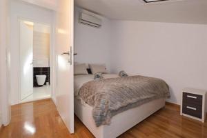 a white bedroom with a bed and a bathroom at Apartment Leo in Ploče +16 photos