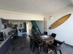a kitchen and dining room with a table and a surfboard on the wall at Appartement spacieux au village du flamboyant in Baie Nettle