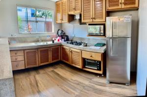 a kitchen with wooden cabinets and a stainless steel refrigerator at Casa amarela 2km de Geribá-Buzios in Búzios