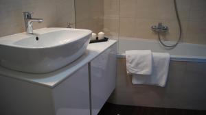 a bathroom with a white sink and a tub at Art Apartment Szczecin in Szczecin