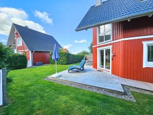 um banco sentado em um deck ao lado de uma casa vermelha em Sechendorf Ferienhaus Solängen Sechendorf em Blekendorf