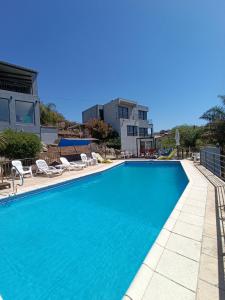 a swimming pool with chairs and a building in the background at Complejo Refugio Playa Perelli in Villa Carlos Paz